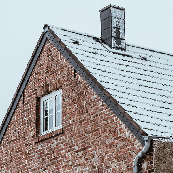 Residential house with a snow-covered roof, representing preventive measures against raccoon intrusion.