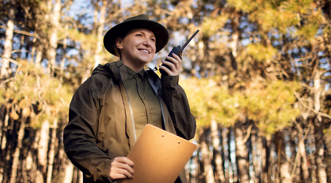 Wildlife professional using a radio in the field, illustrating animal relocation services in urban areas.