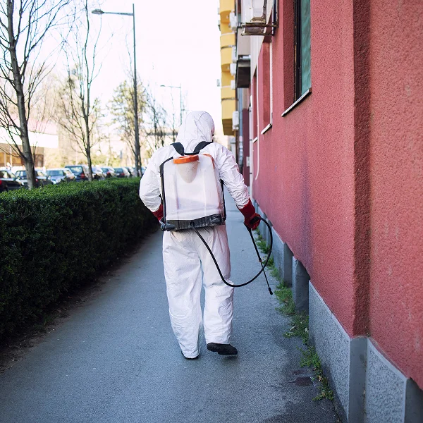 A man in a white suit walking down a sidewalk, promoting an extermination service in Montréal.